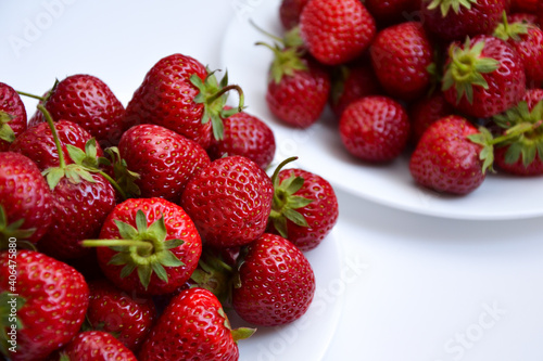 Strawberries on white plate. Freshly picked strawberry. Organic berries on white background. Village garden harvest.