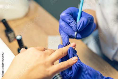 Manicurist doing a manicure in a nail salon  applying varnish on nails