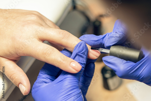 Manicurist doing a manicure in a nail salon  applying varnish on nails