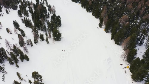 Aerial drone flight tracking skier skiing down the snowy mountain during wintertime in Italy. Active sport session in the mountains. photo