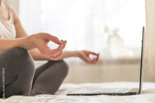a girl with a laptop on the bed doing yoga
