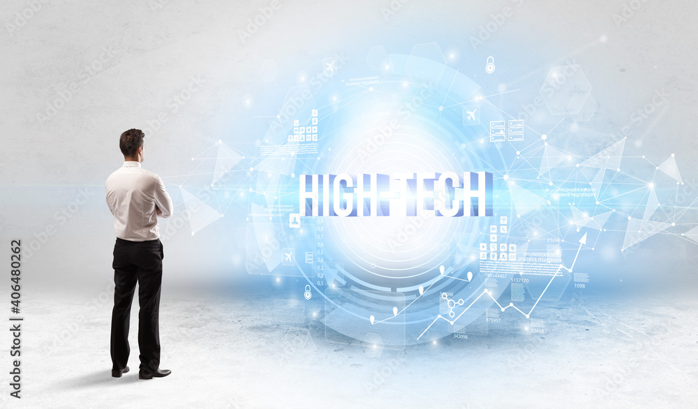 Rear view of a businessman standing in front of HIGH-TECH inscription, modern technology concept Rear view of a businessman standing in front of HIGH-TECH inscription, modern technology concept