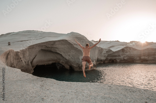 young man jumping from a cliff at Sarakiniko beach on Milos island, Greece