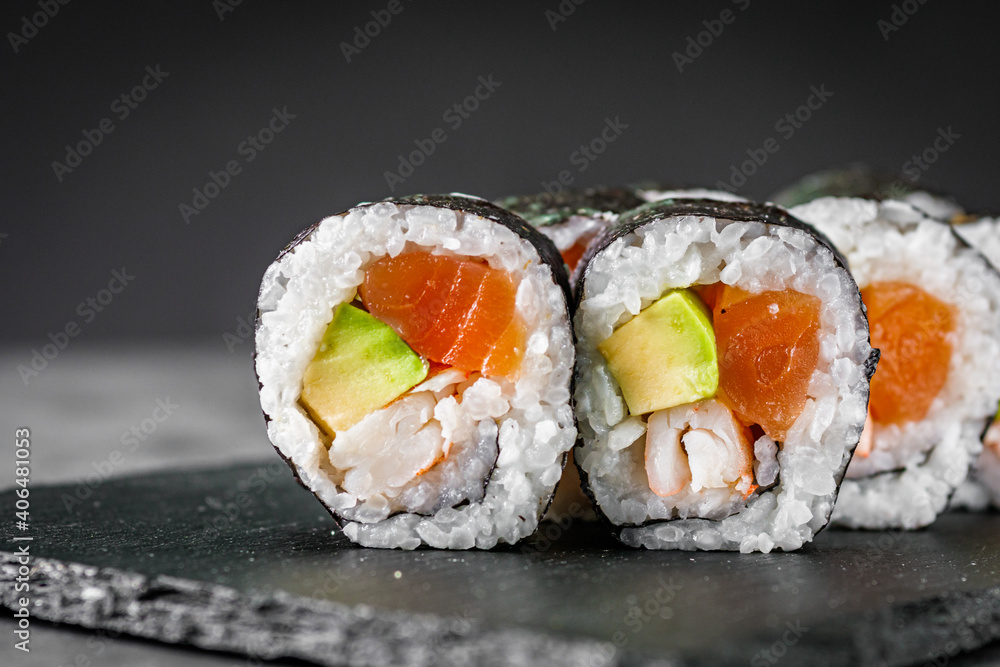appetizing sushi roll futomaki salmon, shrimp and avocado on a black stone plate appetizing sushi roll futomaki salmon, shrimp and avocado on a black stone plate