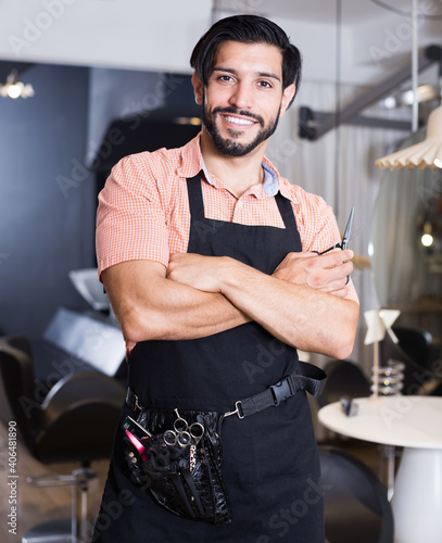 Smiling sexy worker man hairdresser standing in hairdressing studio