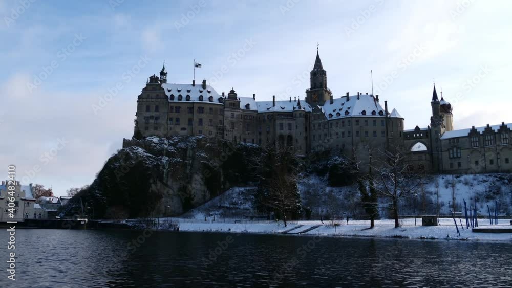 Famous castle located on a rock on the snow-covered shore of Danube River in Sigmaringen, Swabian Alb, Germany in the evening light in winter season with cloudy sky. Famous castle located on a rock on the snow-covered shore of Danube River in Sigmaringen, Swabian Alb, Germany in the evening light in winter season with cloudy sky.
