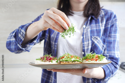 Woman doing healthy vegan toasts with microgreens on a breakfast. © Dmytro