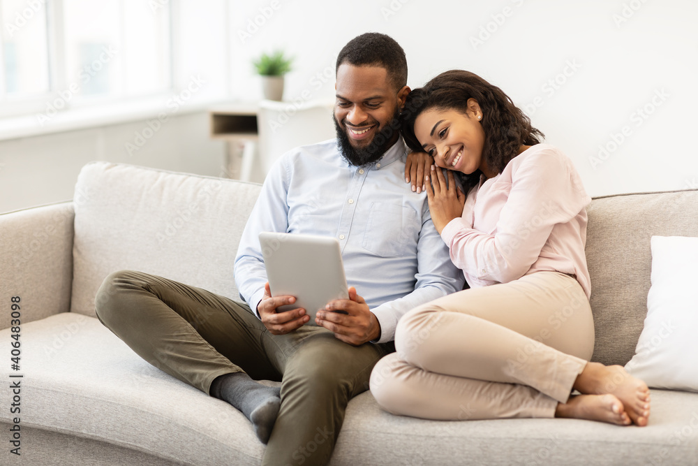 African american couple sitting on couch, using tablet African american couple sitting on couch, using tablet
