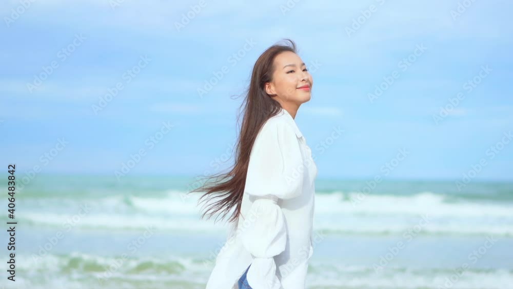 Young girl walking along the beach line. Asian woman enjoying her journey on the beach as she walks along the shore, blurred sea waves on background, slow motion, following shot Young girl walking along the beach line. Asian woman enjoying her journey on the beach as she walks along the shore, blurred sea waves on background, slow motion, following shot