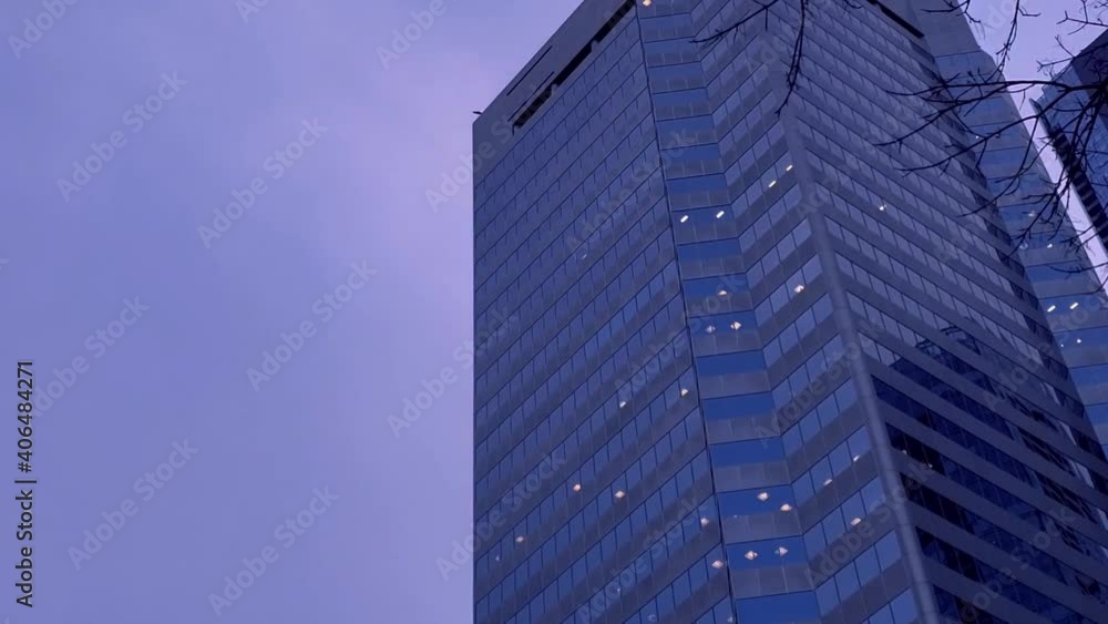 Twilight Skyview Time Lapse purple blu skies in downtown city mirrored reflection of buildings layered with cloud movement and wavy bare branched tree on a fall winter windy cold end of work day Twilight Skyview Time Lapse purple blu skies in downtown city mirrored reflection of buildings layered with cloud movement and wavy bare branched tree on a fall winter windy cold end of work day