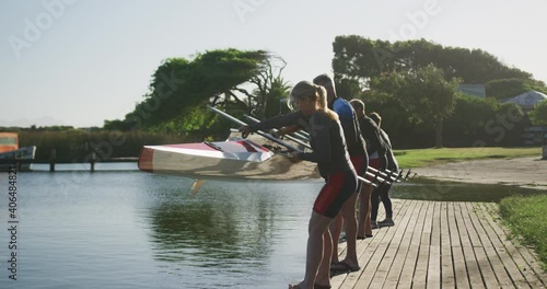 Rowing team of four senior caucasian men and women lowering boat into river photo