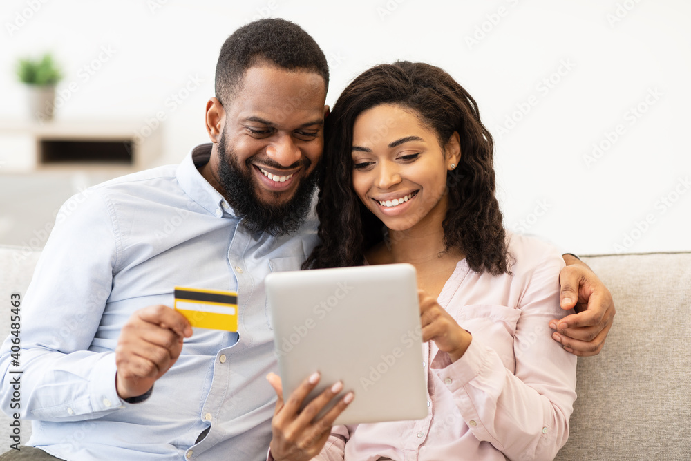 Black couple using tablet and credit card at home Black couple using tablet and credit card at home