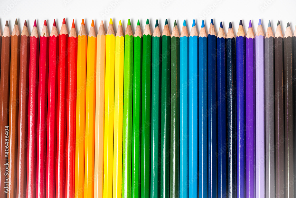 Some different colored wooden pencil crayons placed in a row in front of a white isolated background Some different colored wooden pencil crayons placed in a row in front of a white isolated background