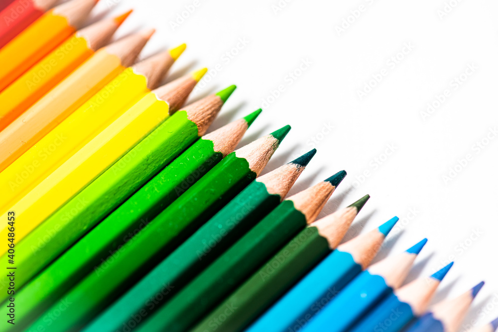 Some different colored wooden pencil crayons placed in a row in front of a white isolated background Some different colored wooden pencil crayons placed in a row in front of a white isolated background