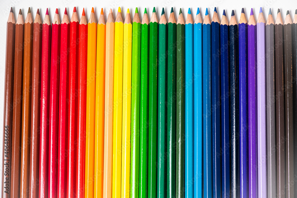 Some different colored wooden pencil crayons placed in a row in front of a white isolated background Some different colored wooden pencil crayons placed in a row in front of a white isolated background