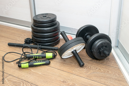 A home gym, dumbbells, ab roller, skipping rope on the wooden floor