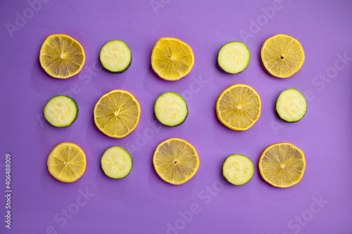 Lemon and cucumber slices on purple background