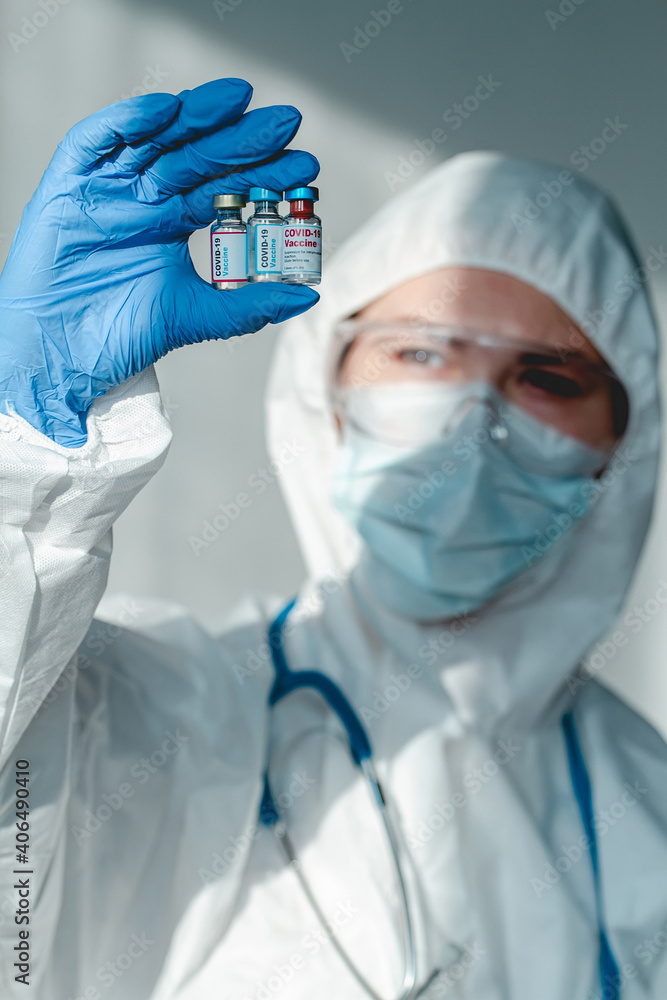 Doctor or nurse in a protective suit holds a covid 19 vaccine from different pharmaceutical companies in hand Doctor or nurse in a protective suit holds a covid 19 vaccine from different pharmaceutical companies in hand