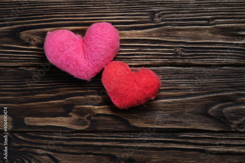 Two woolen handmade hearts on the dark brown wooden boards