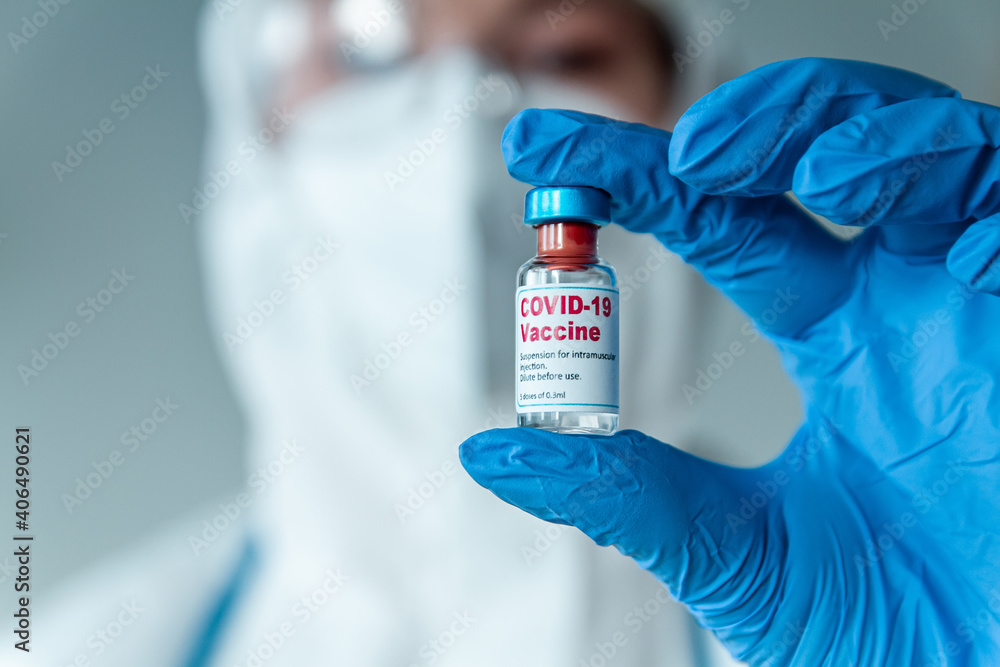 Doctor or nurse in a protective suit holding a covid 19 vaccine Doctor or nurse in a protective suit holding a covid 19 vaccine