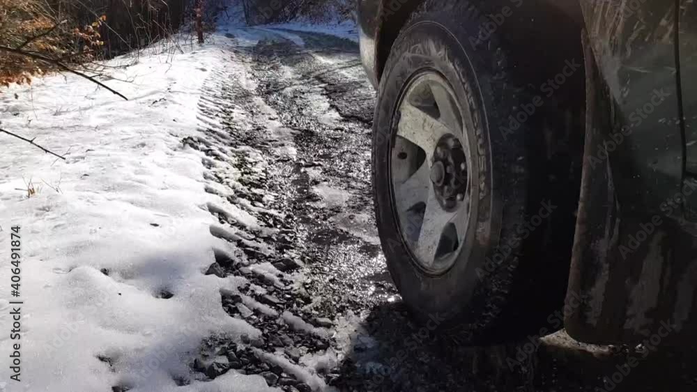 Left Front Wheel Of A 4x4 Vehicle Travelling On Snowy Road In The Mountain In Winter, close up Left Front Wheel Of A 4x4 Vehicle Travelling On Snowy Road In The Mountain In Winter, close up