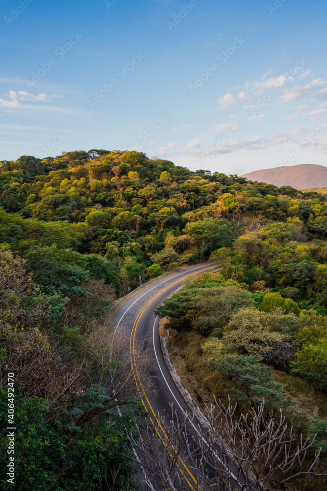 road next to a hill in the daytime.