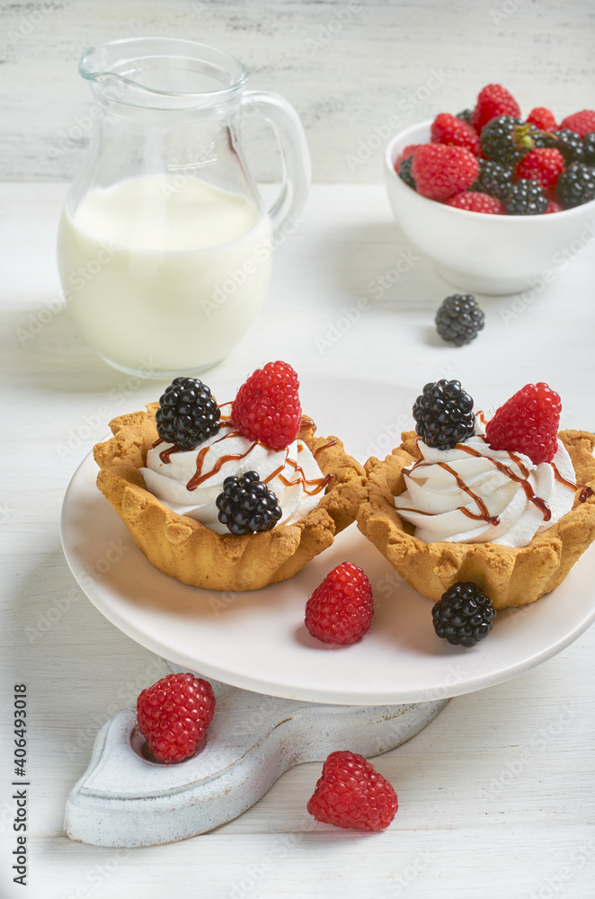 Two cakes on a light plate with blackberries and raspberries. Two cakes on a light plate with blackberries and raspberries.