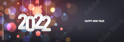 Happy new year 2022. Hanging white paper number on a horizontal colorful blurry background.
