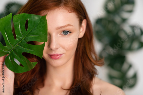Red-Haired Young Woman Posing With Tropical Leaf Over White Background