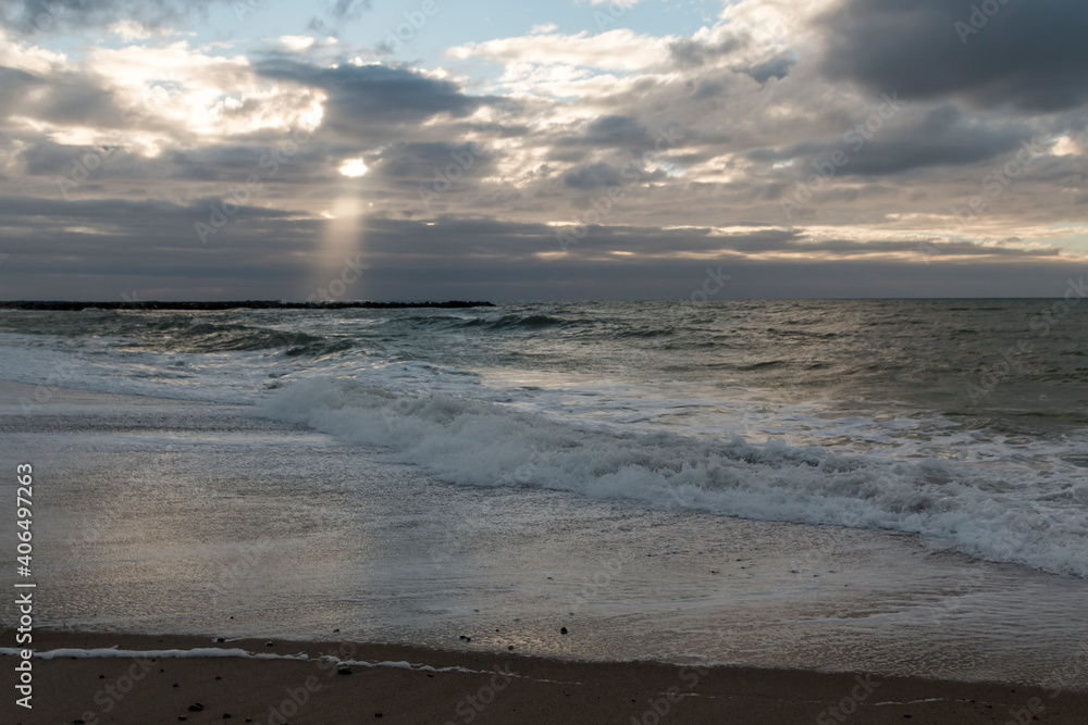 Coast line at Thyboron on the Danish west coast, clouds in the sky, waves in the sea, white foam splashes, rocks