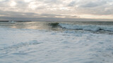 Coast line at Thyboron on the Danish west coast, clouds in the sky, waves in the sea, white foam splashes, rocks