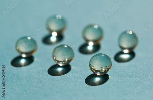 Spherical transparent pills on a blue background in the sunlight. Hard shadows.