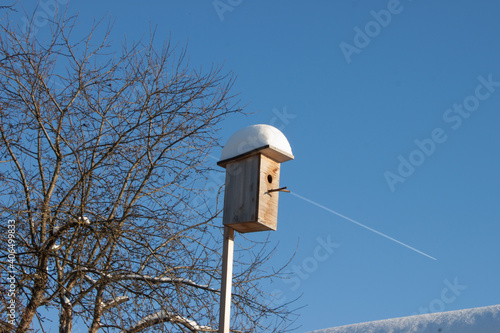 Old rusty birdhouse with snowdrift on the roof hanging on the fir. Feeding animals at winter