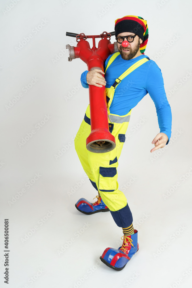 The clown firefighter holds a fire pump in his hands. The clown firefighter holds a fire pump in his hands.