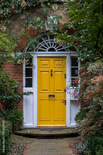 Canvas Print Garden path leading to yellow door in traditional British house