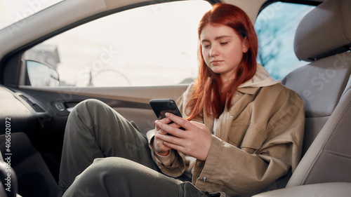 Portrait of teenage girl looking at the screen while using her phone, sitting in the car. Smartphone addiction concept © Svitlana