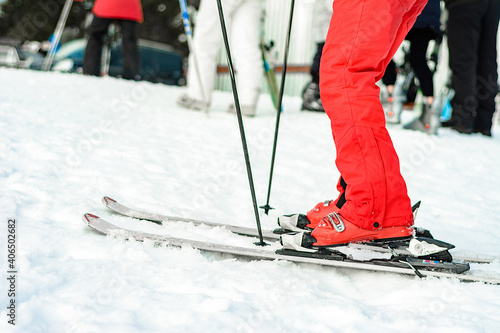 Ski, boots and sticks in red on a woman's leg close up.
