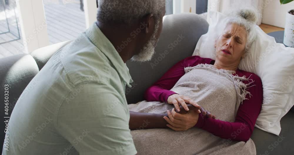 African american man taking care of his sick wife in the living room at home African american man taking care of his sick wife in the living room at home