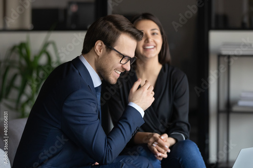 Close up happy diverse colleagues chatting, excited businessman wearing glasses and Indian businesswoman laughing at joke, discussing funny news, employees having fun during break in modern office © fizkes