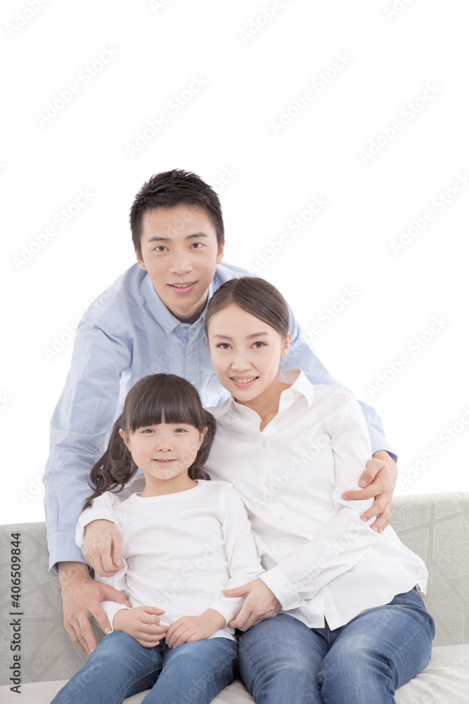 Portrait of mother sitting on sofa with daughter, father behind Portrait of mother sitting on sofa with daughter, father behind