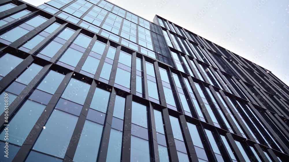 Facade of a modern office building during snowfall from the bottom up