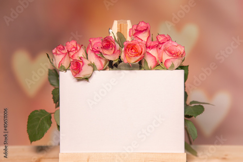 Pink roses on a wooden background, white place for text, easel, pink background for the holiday of February 14 or March 8