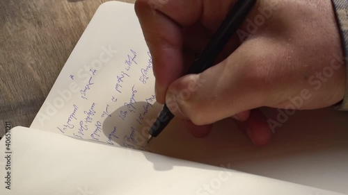 Person writing with a pen Georgian script on a notebook - High angle Close up photo