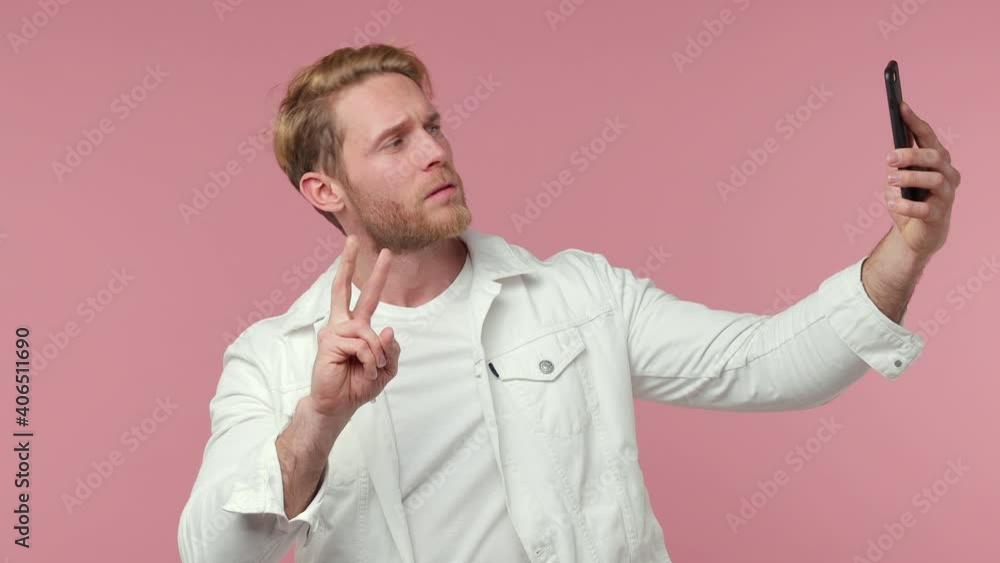 Funny bearded young man 20s in white clothes isolated on pink background studio. People lifestyle concept. Doing selfie shot on mobile phone showing biceps muscles thumb up victory sign point himself Funny bearded young man 20s in white clothes isolated on pink background studio. People lifestyle concept. Doing selfie shot on mobile phone showing biceps muscles thumb up victory sign point himself
