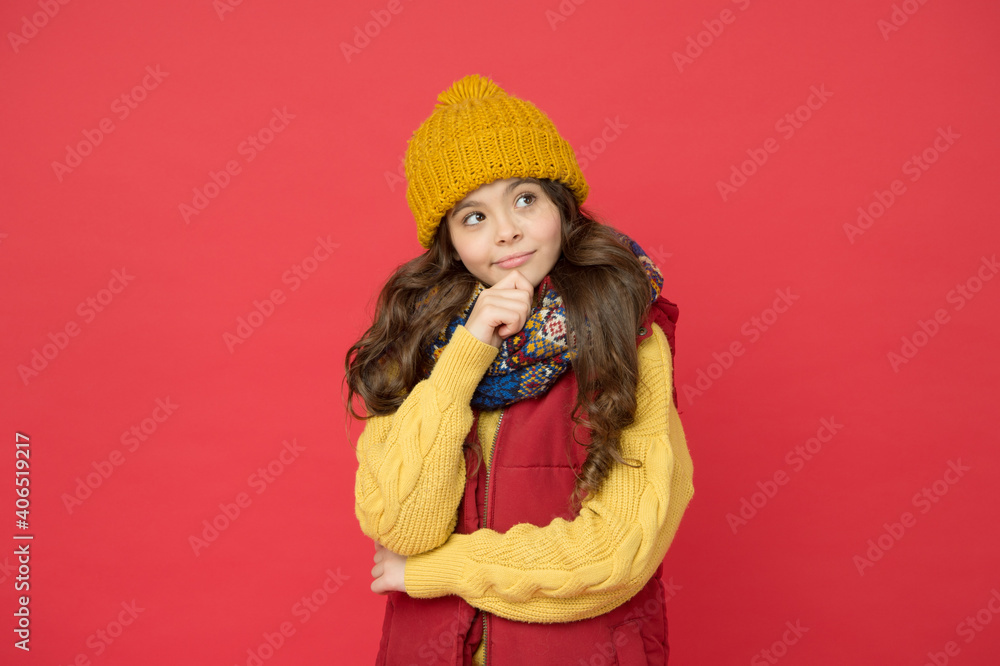 pretty kid girl in puffer waistcoat with knitted hat and sweater, winter time