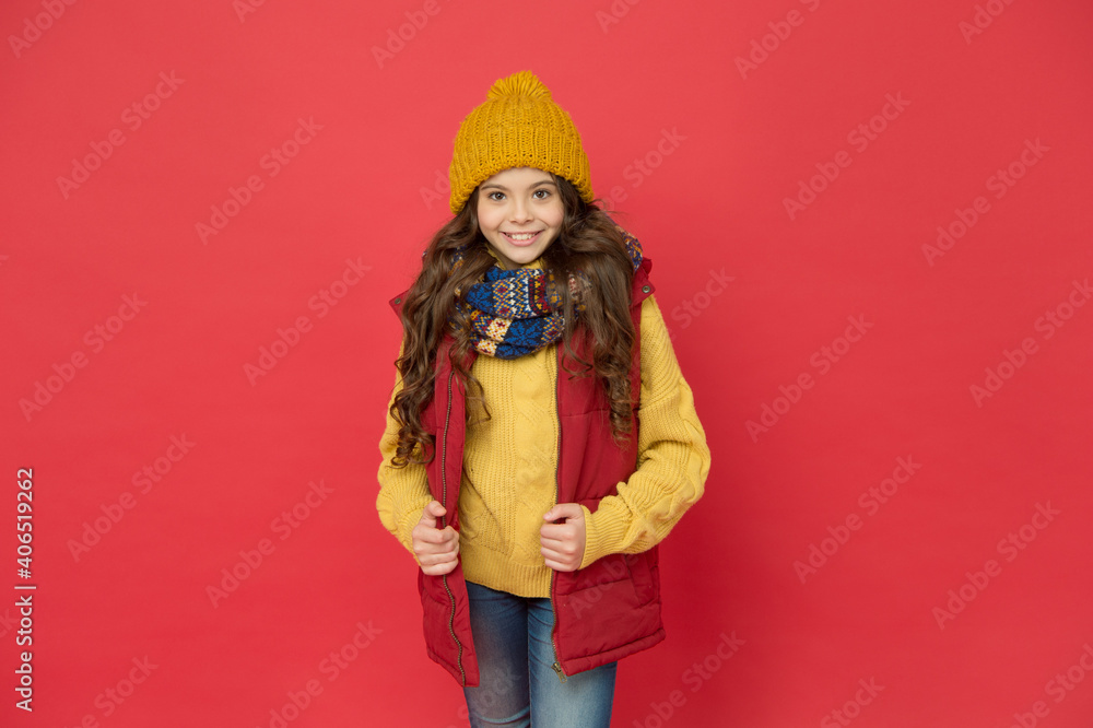 pretty kid girl in puffer waistcoat with knitted hat and sweater, kid fashion