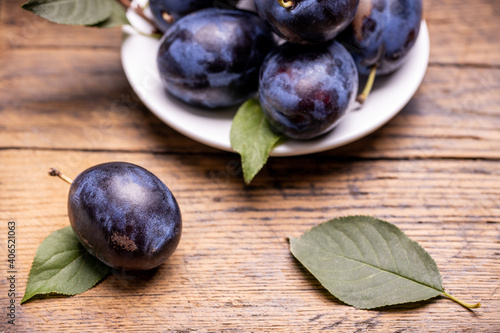 heap of a purple damsons plums over grunge wooden background. natural fruits. healthy eating concept