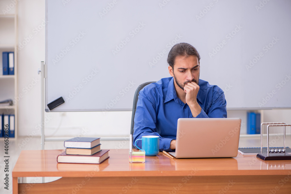 Young male teacher physicist sitting in the classroom Young male teacher physicist sitting in the classroom
