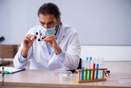 Young male chemist teacher sitting in the classroom