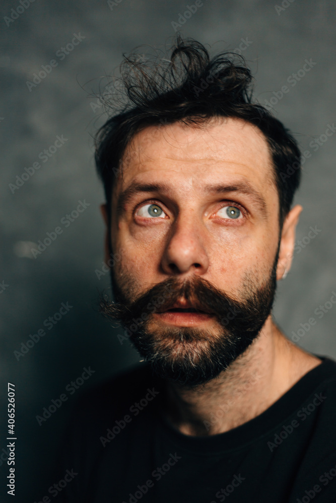 Portrait of a courageous guy with a beard and mustache on a canvas background